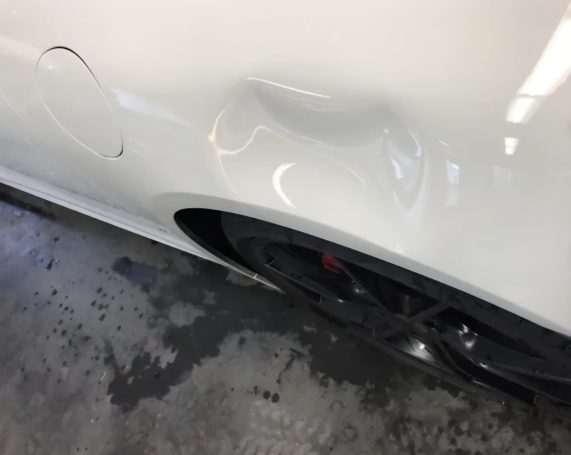 Beschädigter hinterer Kotflügel eines Porsche mit Karosseriedelle